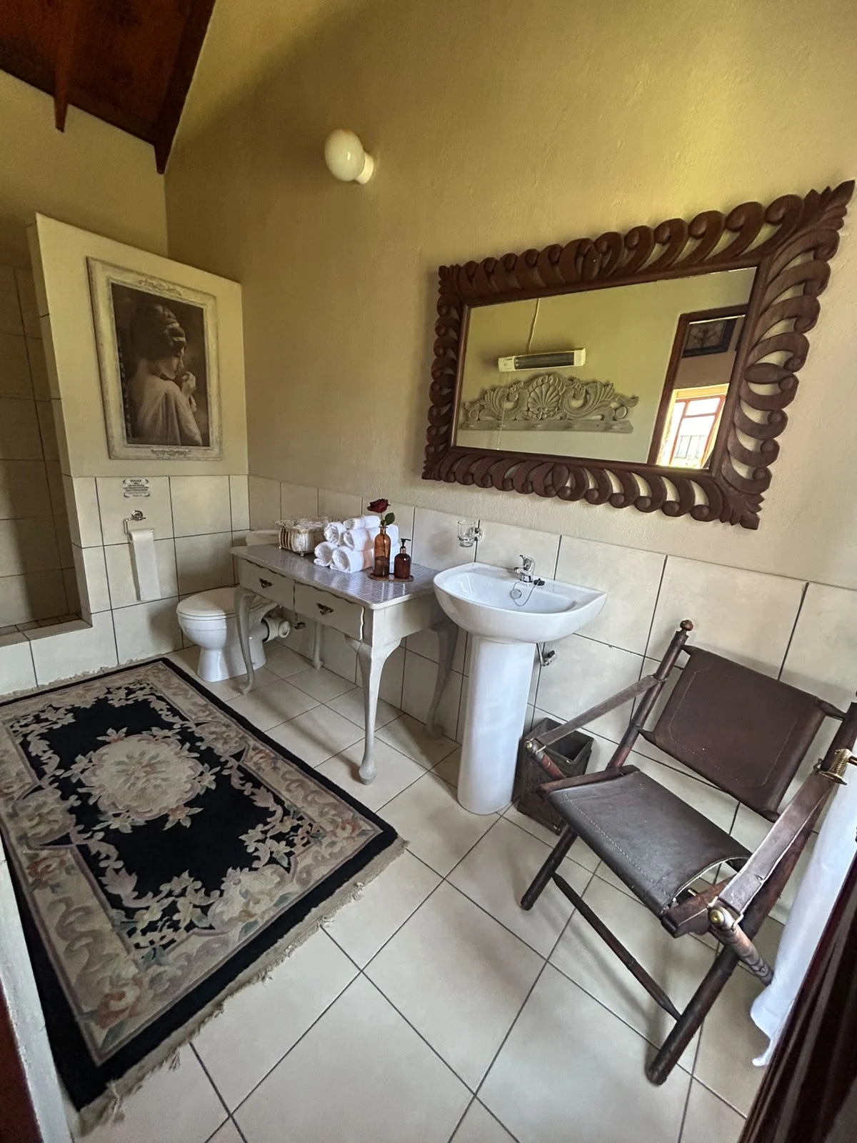 Bathroom basin and toilet beneath a dark framed mirror