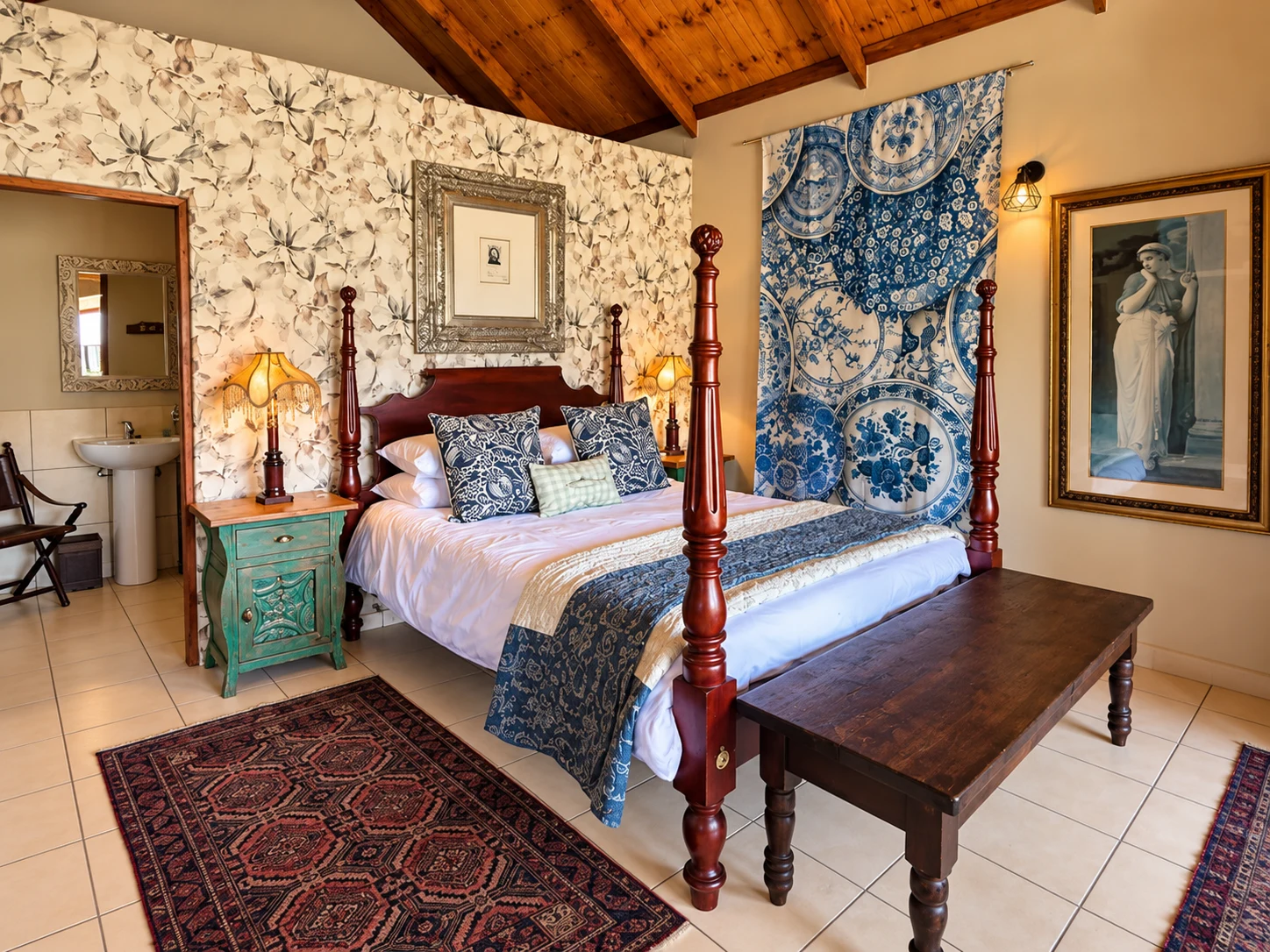 Four-poster bed with blue patterned textiles and floral wallpaper