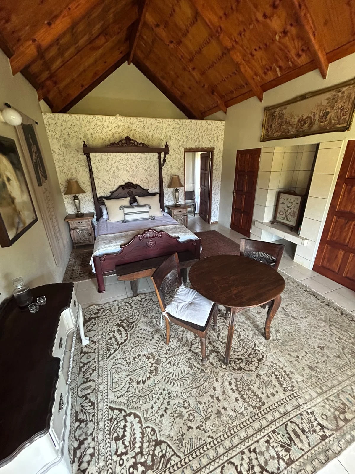 Ornately carved four-poster bed, round table and persian carpet