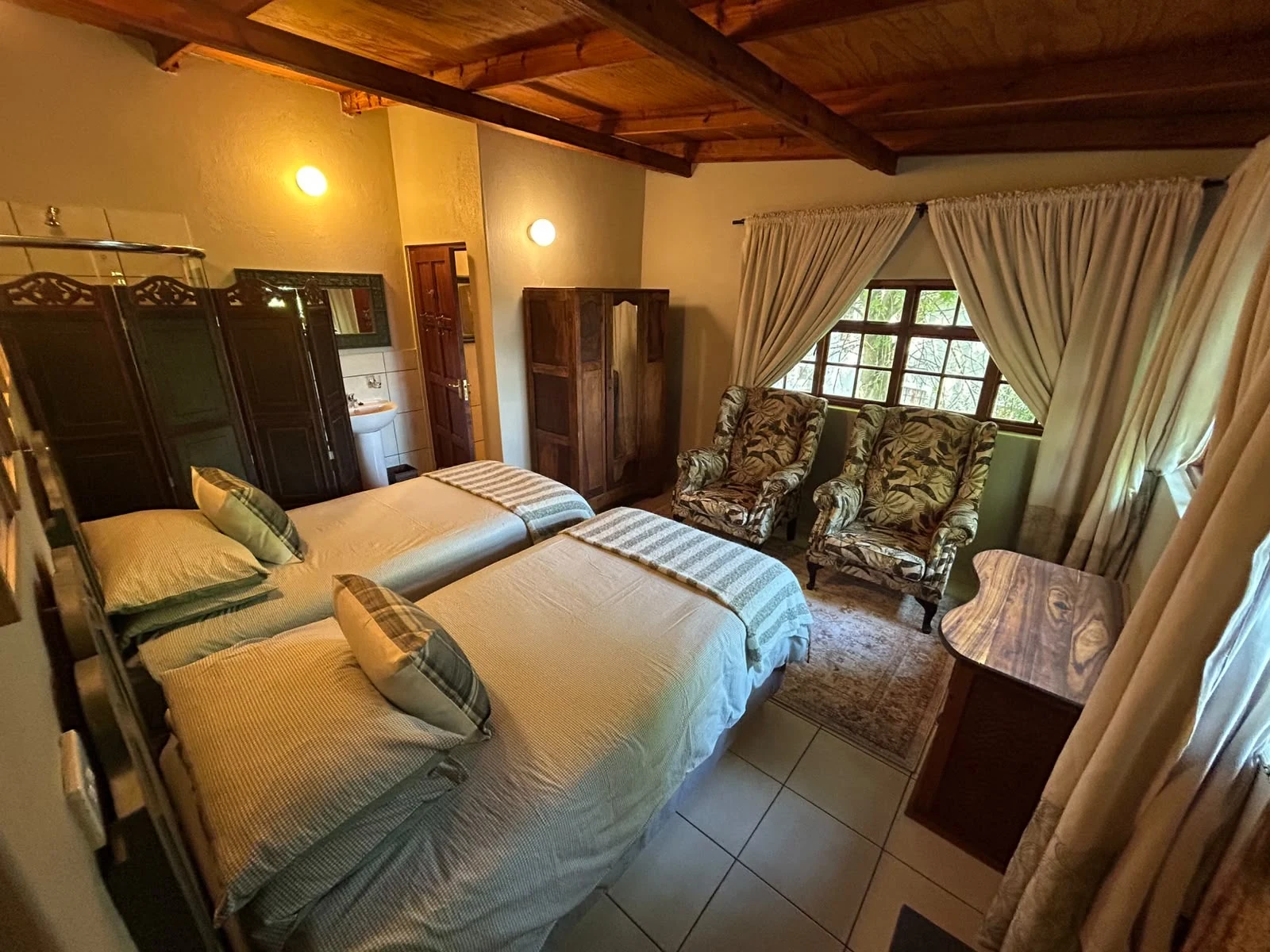 Twin room viewed towards the window and two patterned armchairs